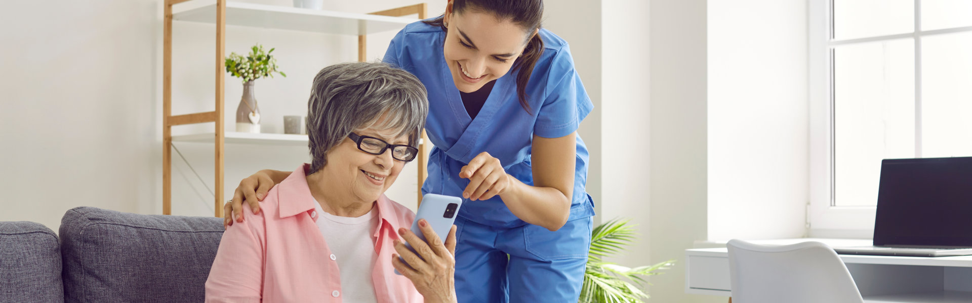 aide assisting the senior woman on her mobile phone